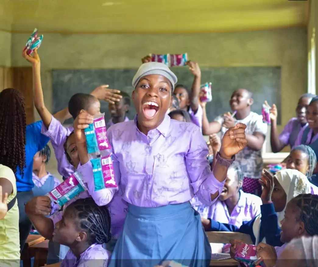 A picture of a student happily recieving sanitary pads.